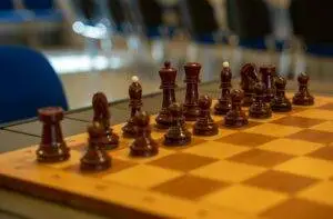 Close-up of a chessboard with neatly arranged wooden chess pieces in an indoor setting.