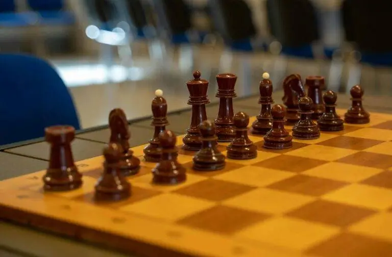 Close-up of a chessboard with neatly arranged wooden chess pieces in an indoor setting.