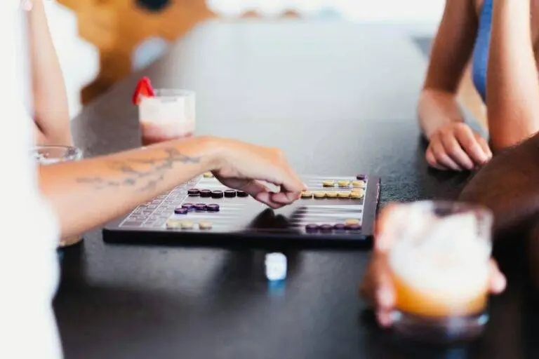 A detailed close-up of friends enjoying a board game and cocktails at a bar counter, creating a lively and social atmosphere.