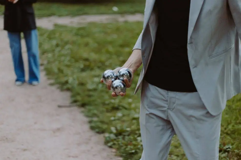 A person holding stainless steel boules on a park pathway, ready to play.