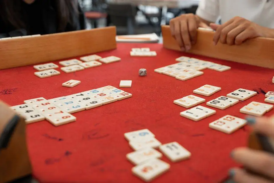 Hands playing Rummikub with numbered tiles, fostering fun and strategy in a vibrant setting.