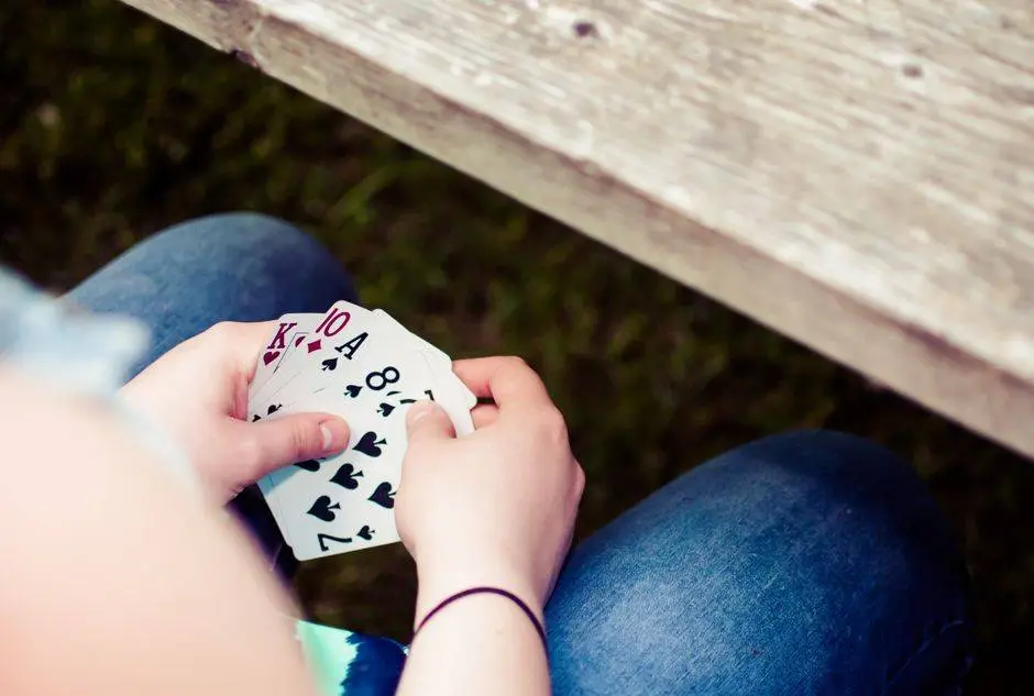 Person holding playing cards at an outdoor setting, showing a hand of cards.
