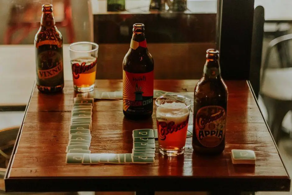 Three craft beer bottles and glasses on a wooden table with game pieces, set in an indoor Brazilian location.