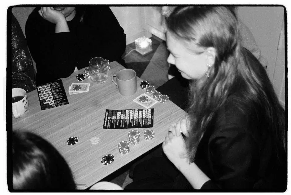 Group of friends enjoying a casual poker night indoors, captured in black and white.