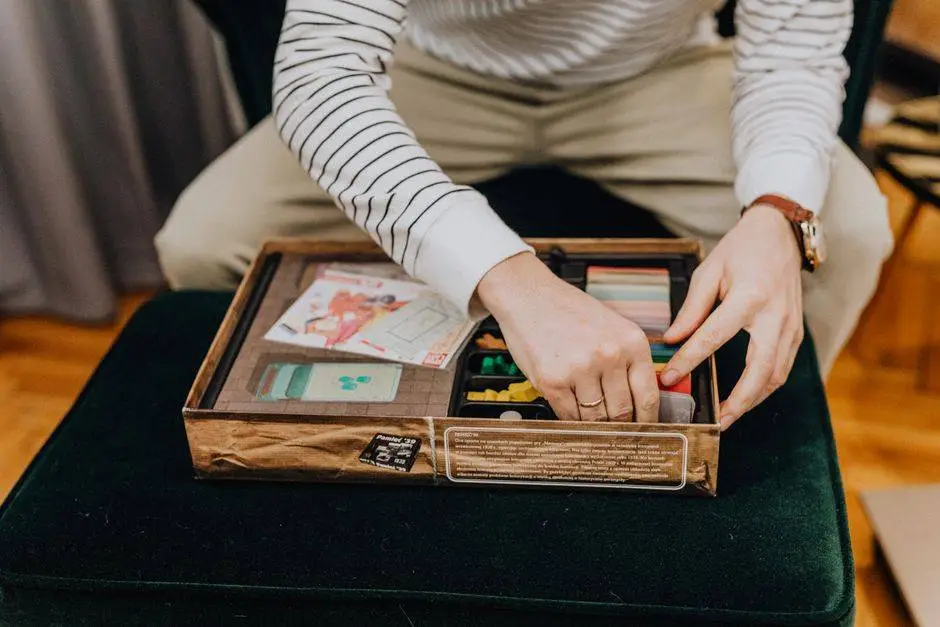 Close-up of an adult setting up a board game indoors for leisure and entertainment.
