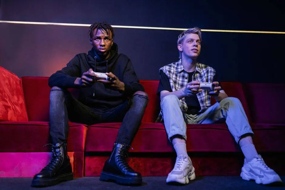 Two young men enjoying video games together on a vibrant red couch indoors.